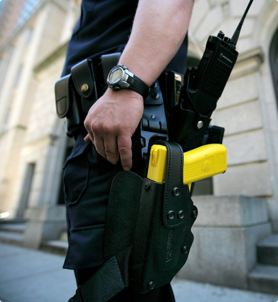 Image of a policeman wearing a stun gun on a holster out in the street.