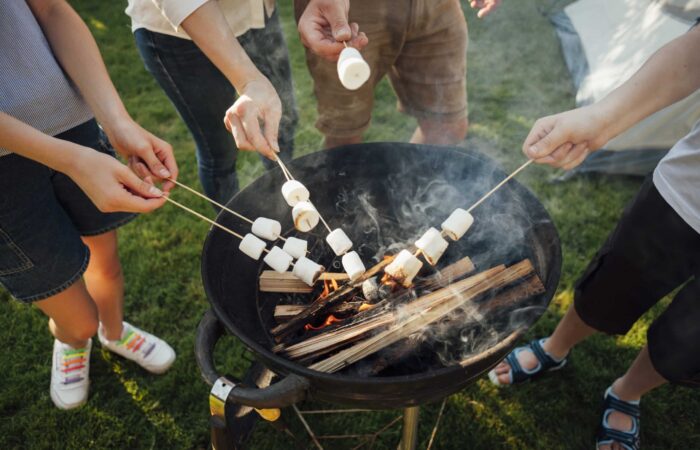 elevated-view-hands-roasting-marshmallow-barbecue-fire lightened using a grill lighter